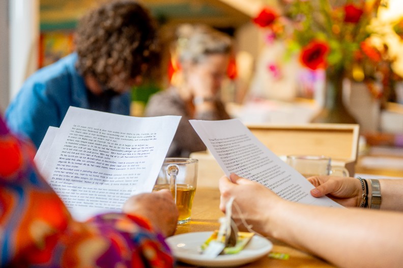 Twee mannen net baarden zijn bezig met armworstelen in een café-achtige setting 